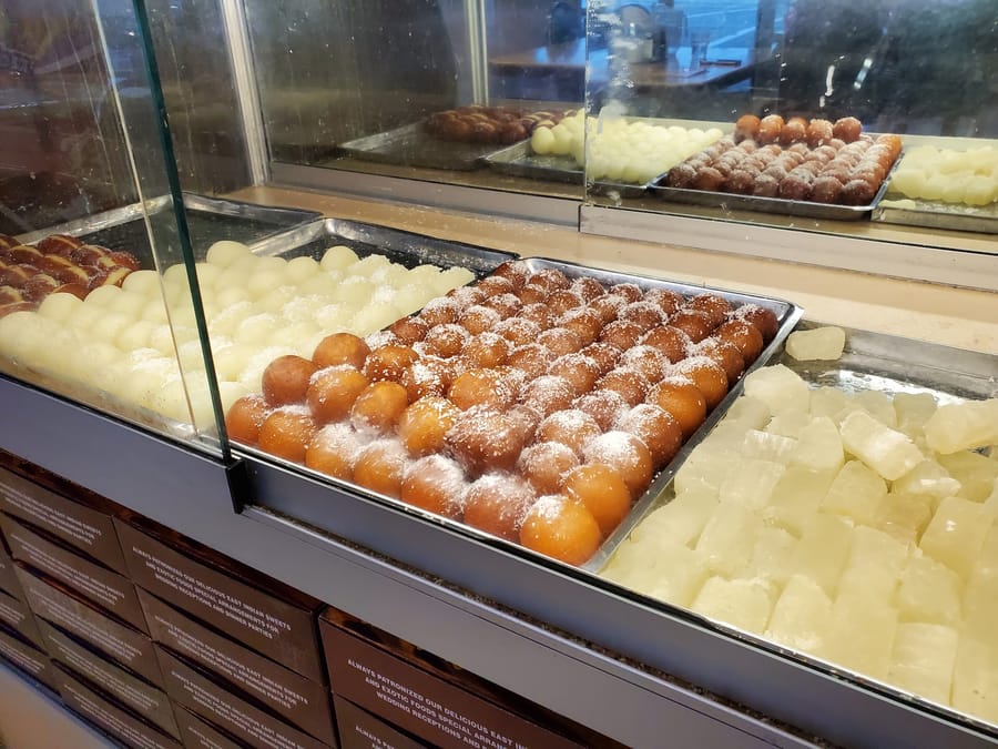 Gulab jamun and white sweets in the display case